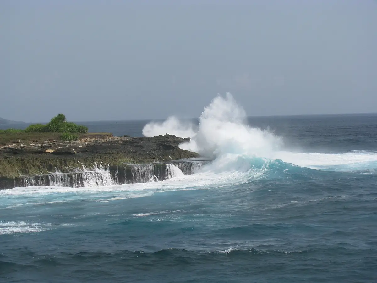 A wave bursting over the rocky coast of Nusa Lembongan